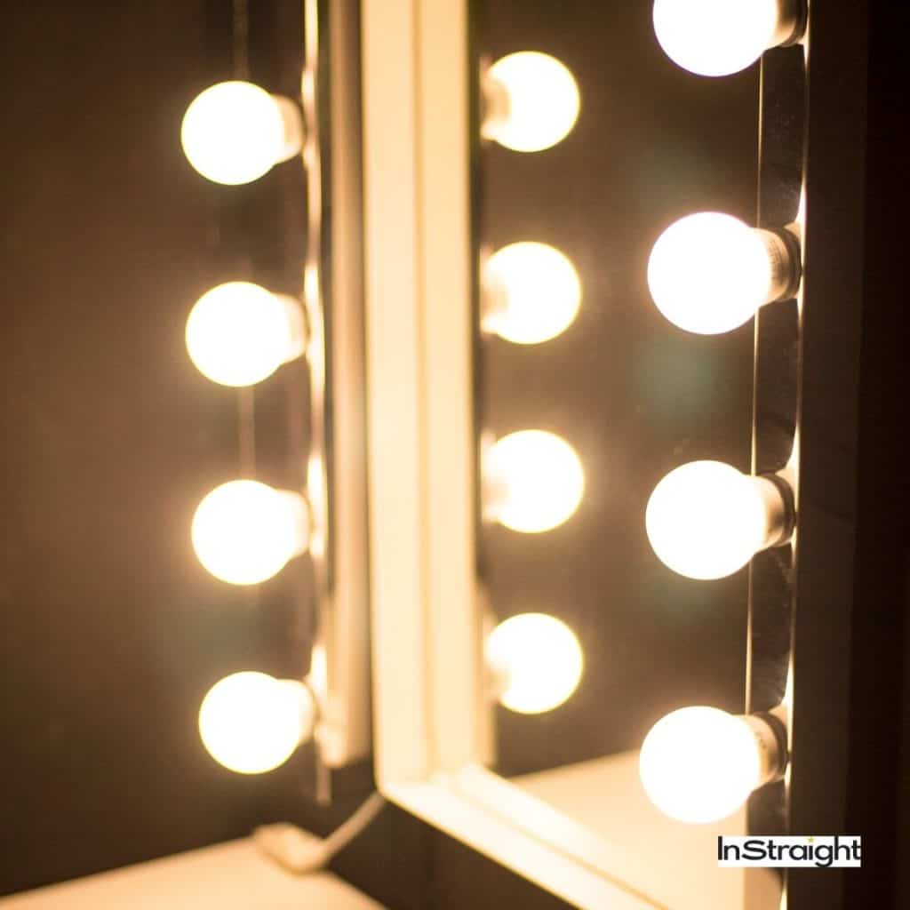 lit mirror with bulbs on the front side under title What's the Difference Between Backlit And Lighted Mirrors